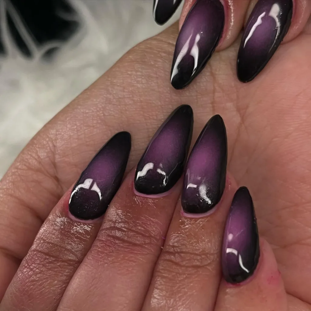 purple and black almond nails with a magnetic cat-eye accent