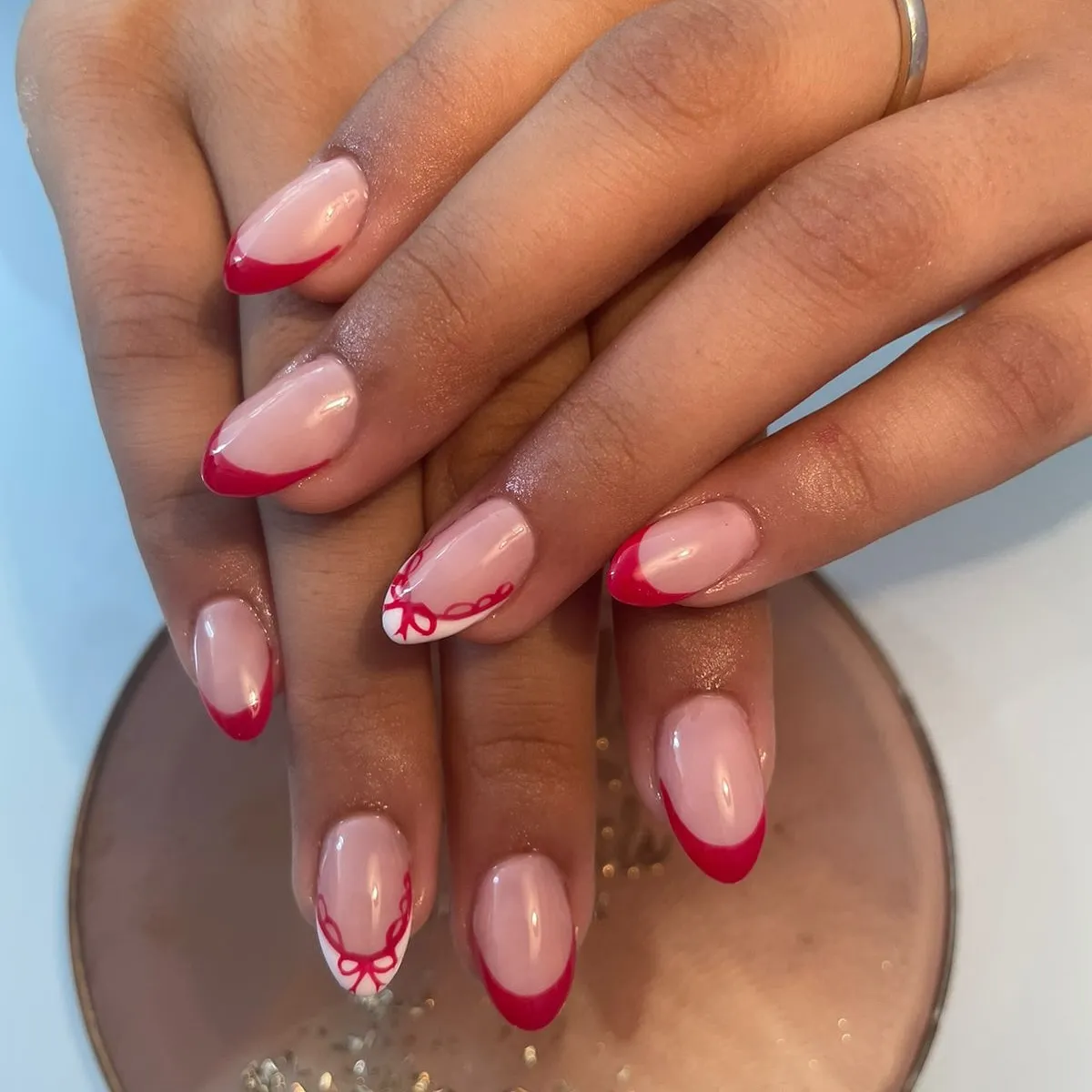 Red French almond nails with a red bow accent