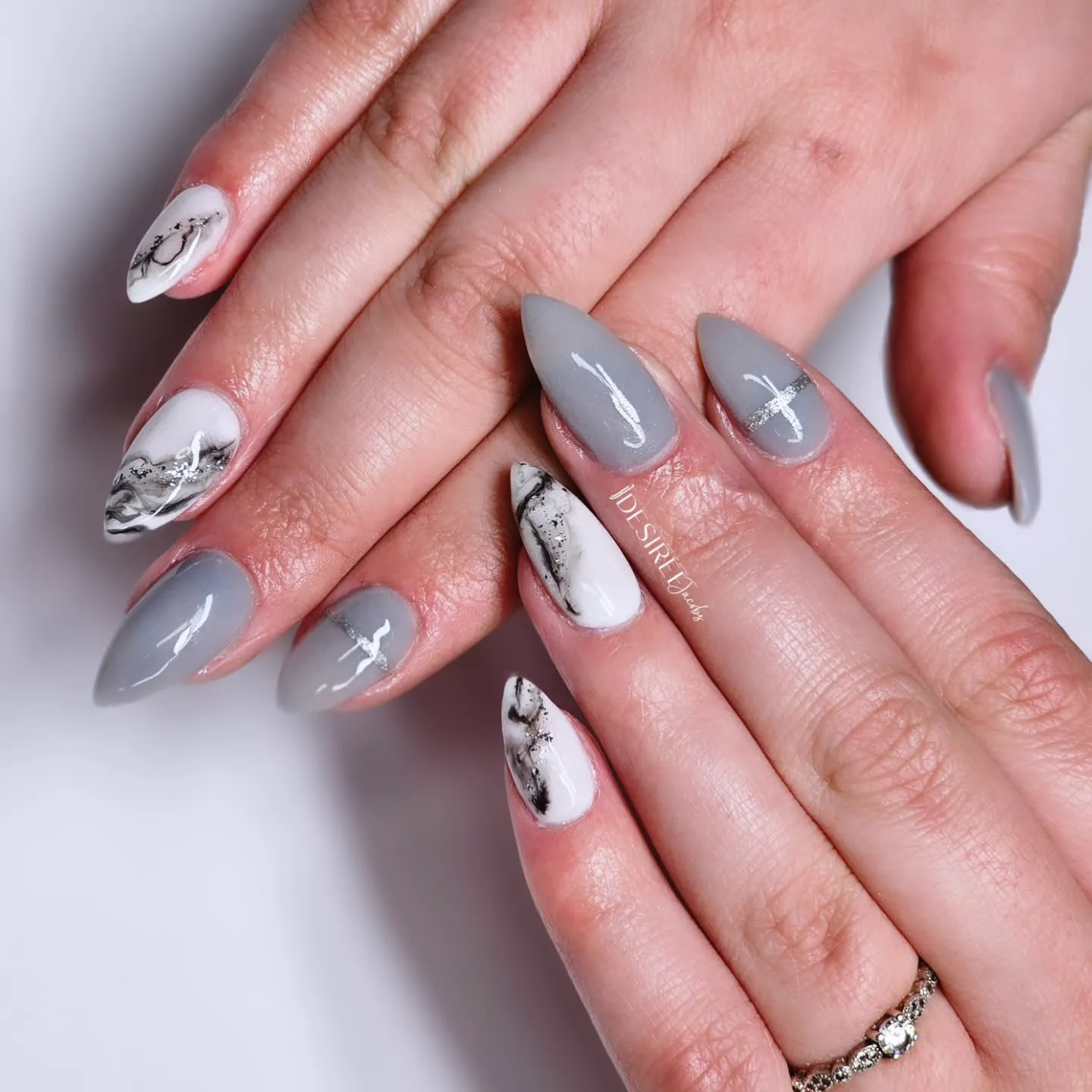 White marble accent nails paired with solid gray almond nails