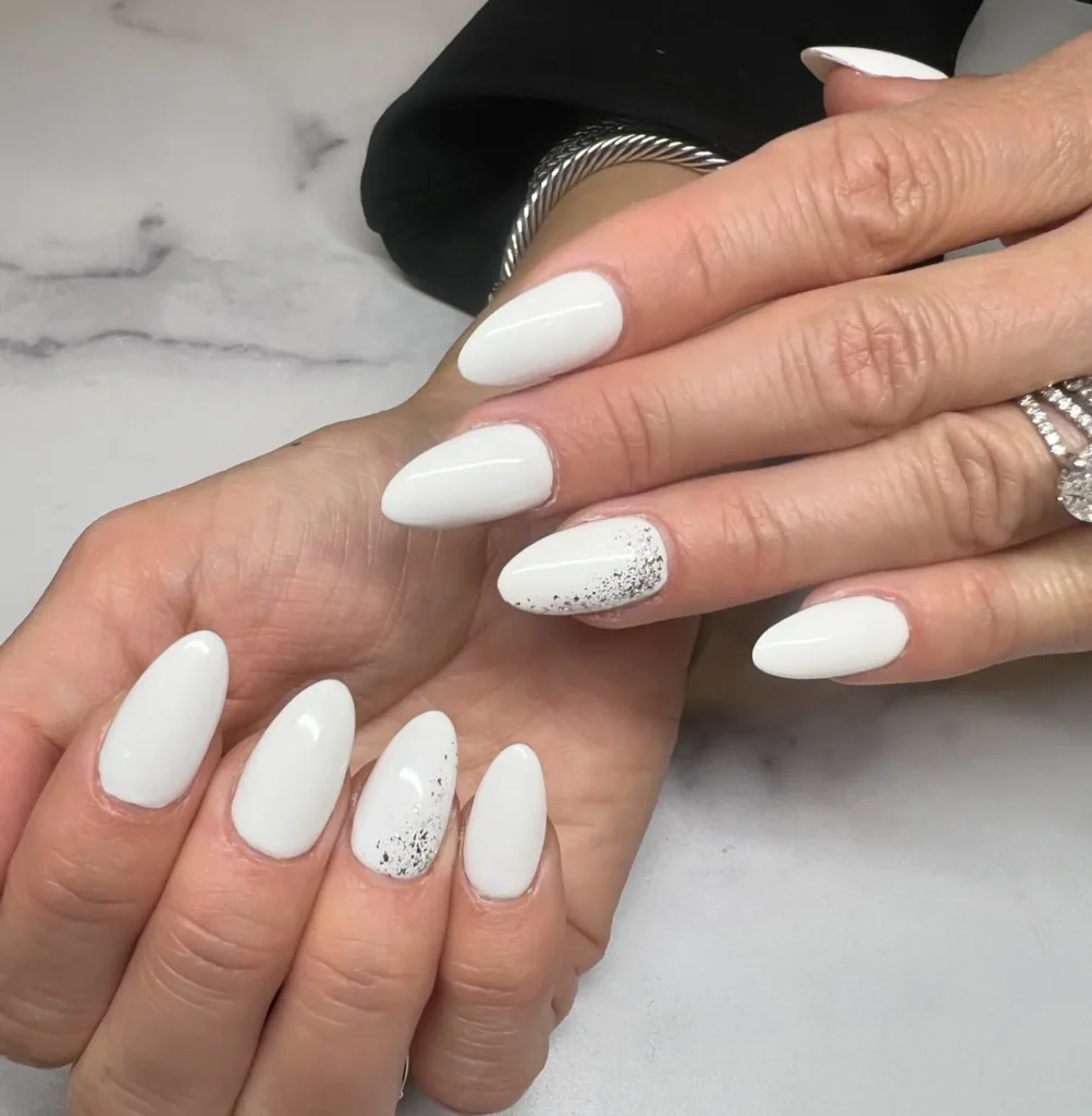 classic glossy white long almond nails with a speckled accent nail