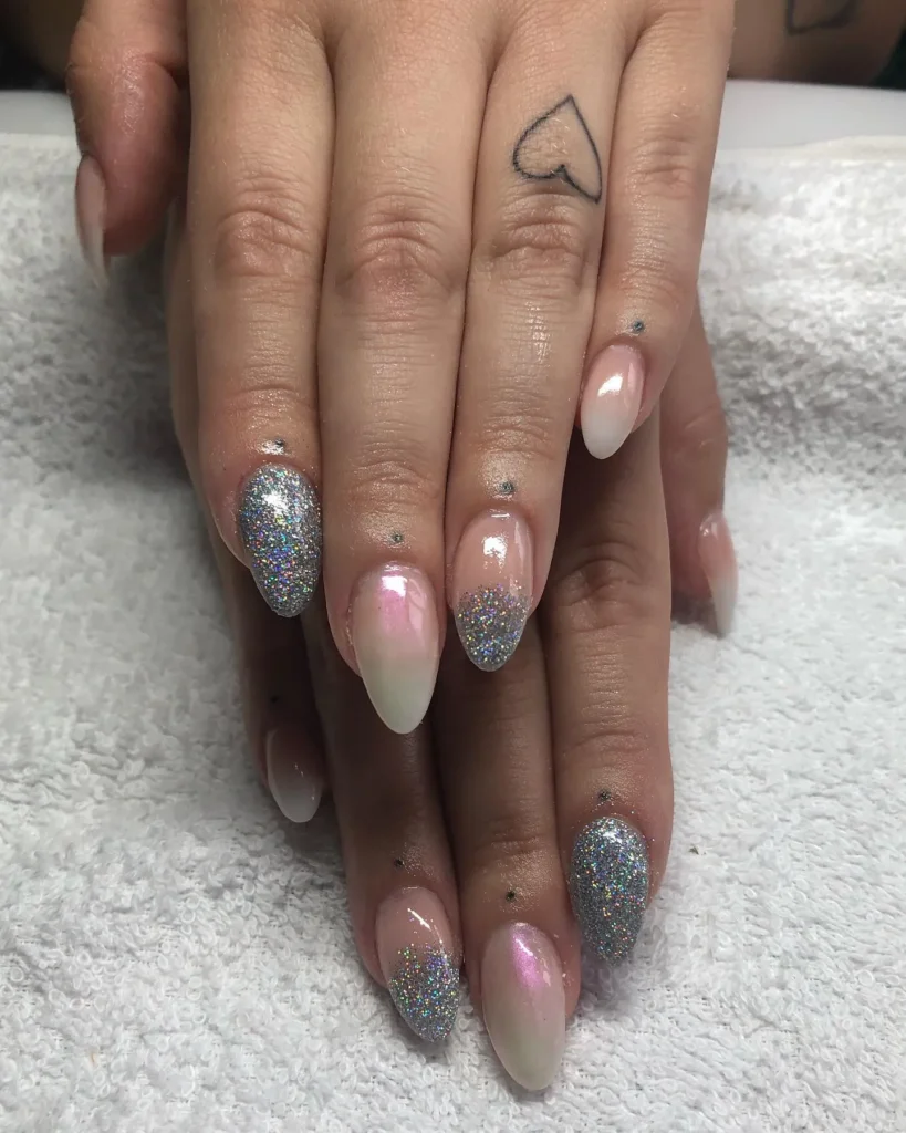 nude almond nails with silver glitter fading in at the tips