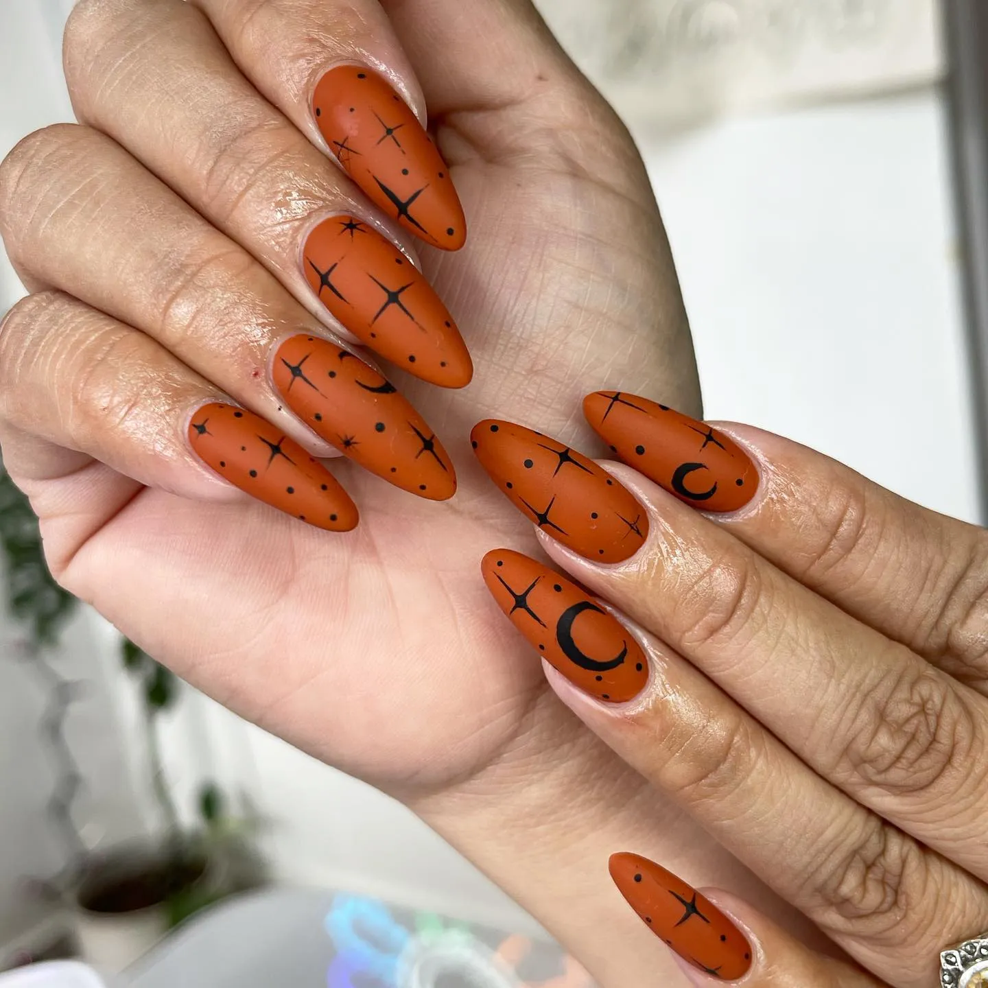 Burnt orange nails with black crescent moons and stars