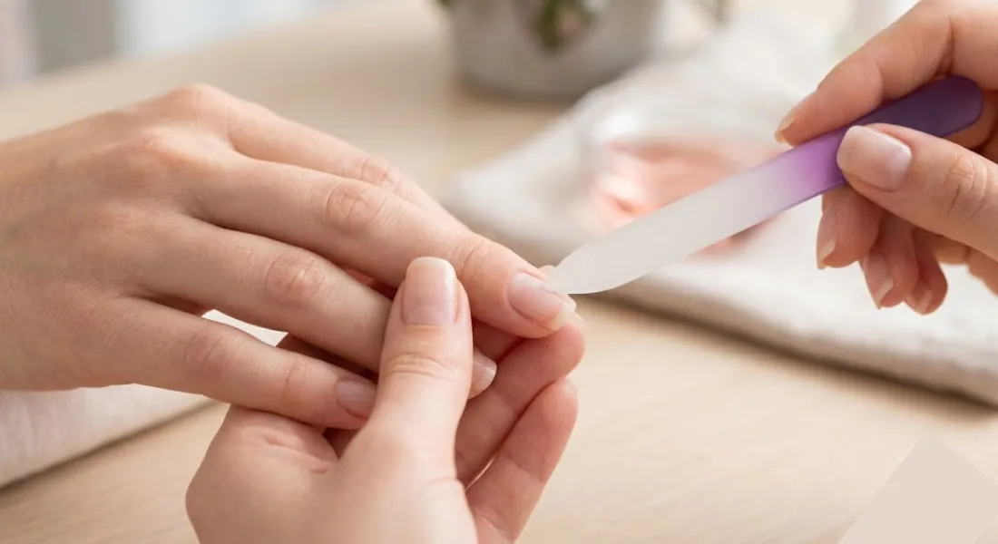 How to File Nails Properly (Without Weakening Them) - hand filing a nail in a single, smooth direction