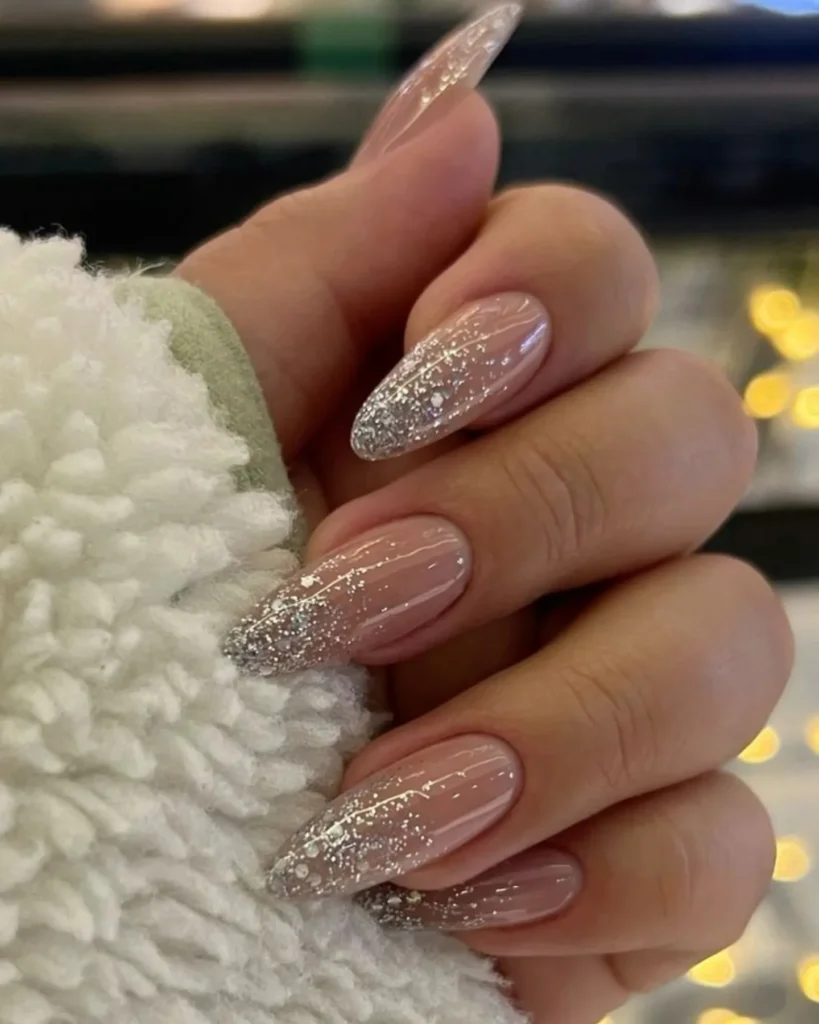 silver glitter ombre fading into a French tip on almond nails