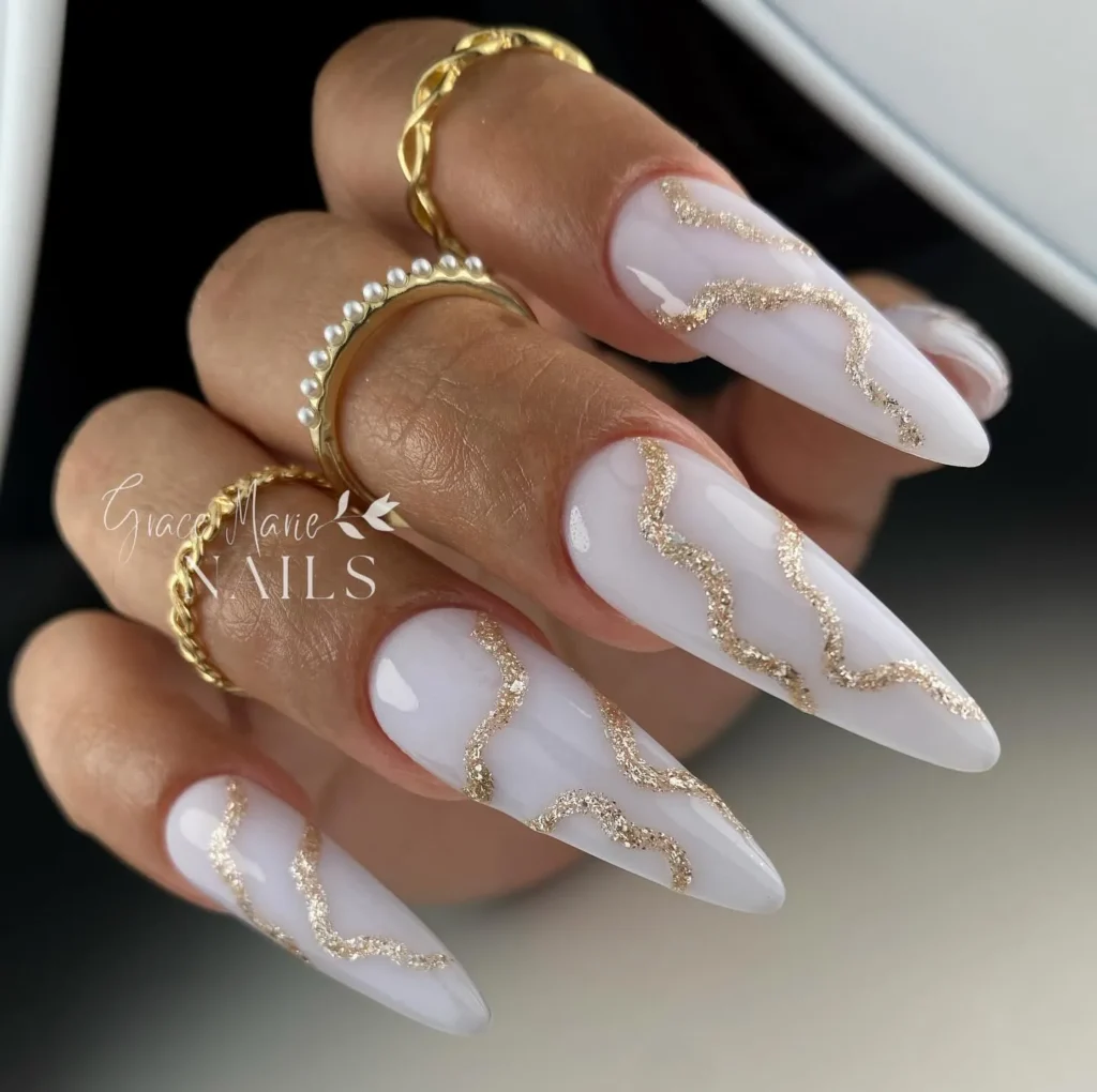 milky white long almond nails with a gold foil swirl line art design