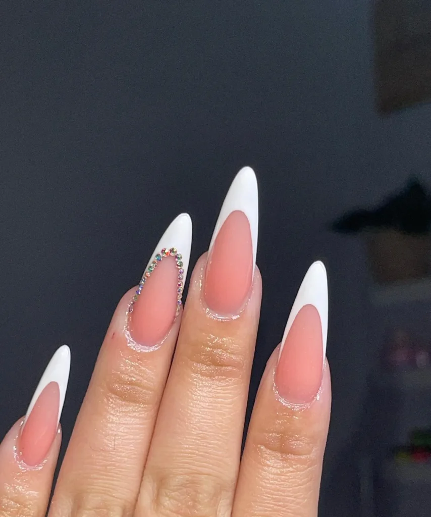 curved white French tip long almond nails with a single rainbow rhinestone accent nail