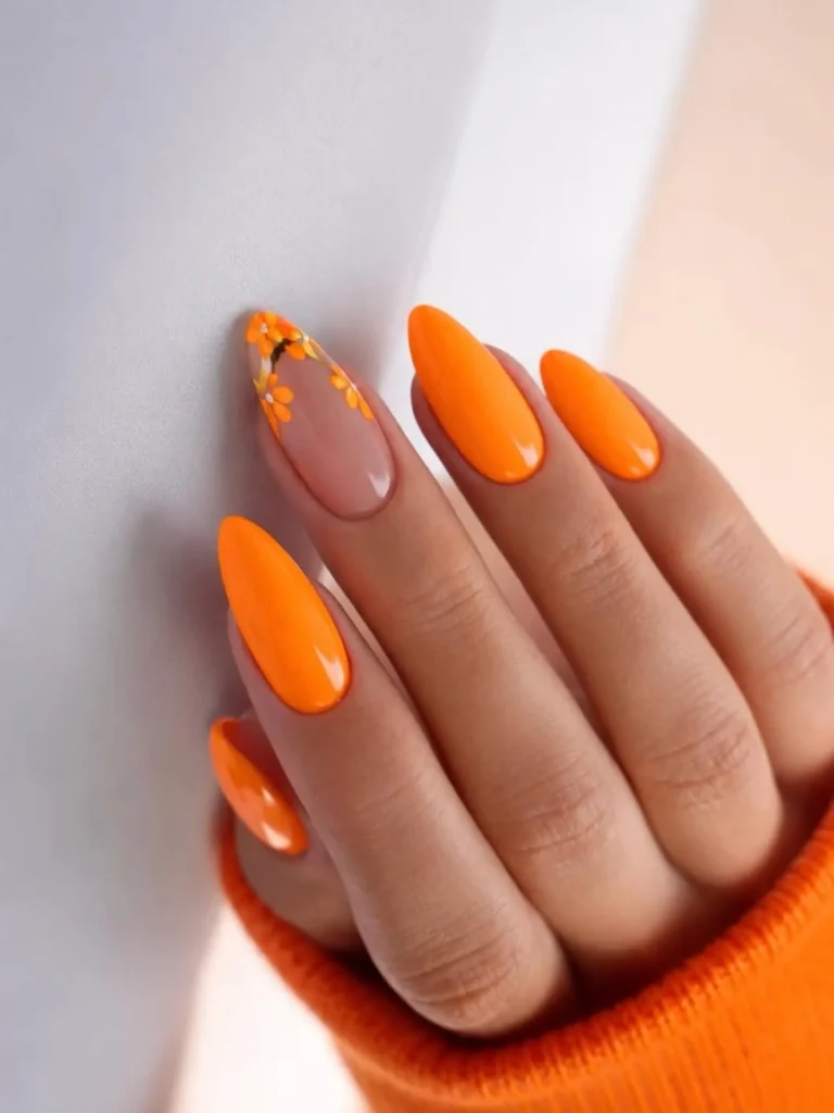 glossy solid orange almond nails with a delicate hand-painted floral accent nail