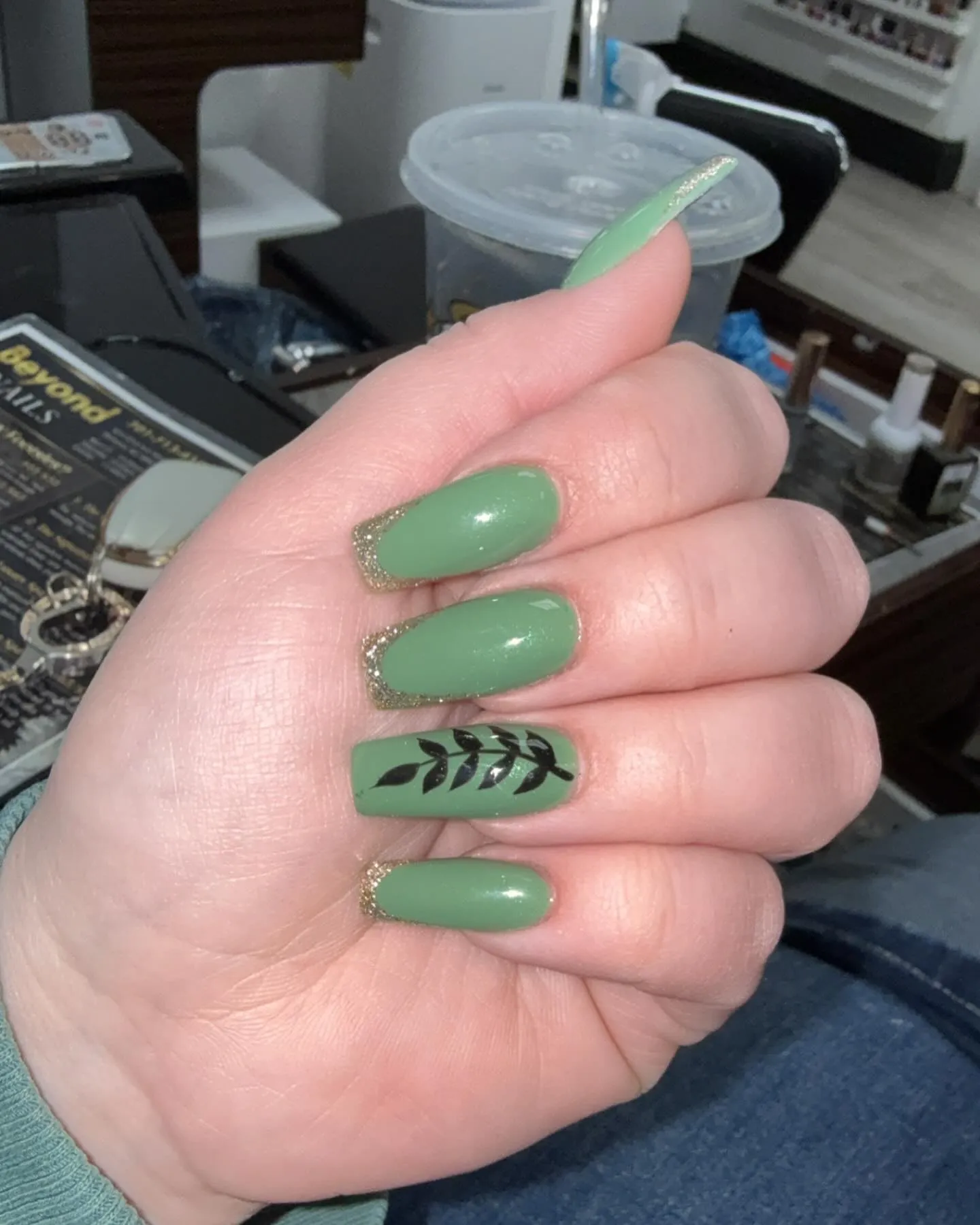 Sage Green Coffin Nails with Gold Glitter Edge and Leaf Accent