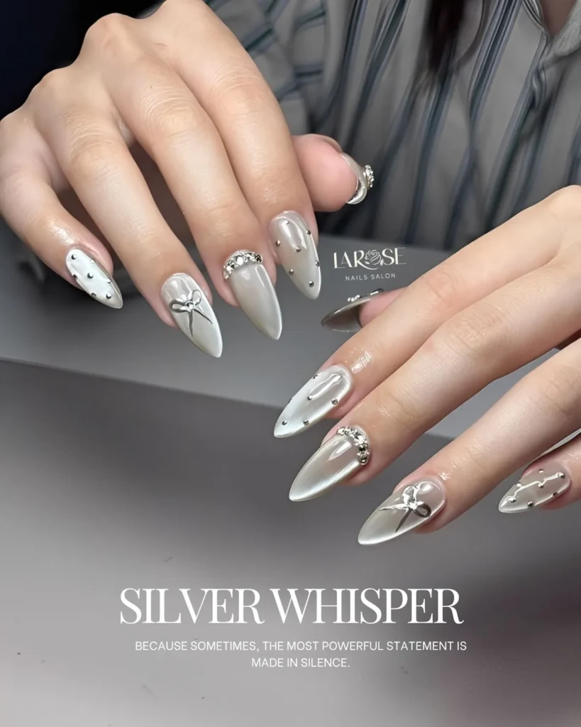 soft chrome silver almond nails with a nude accent and crystal placements