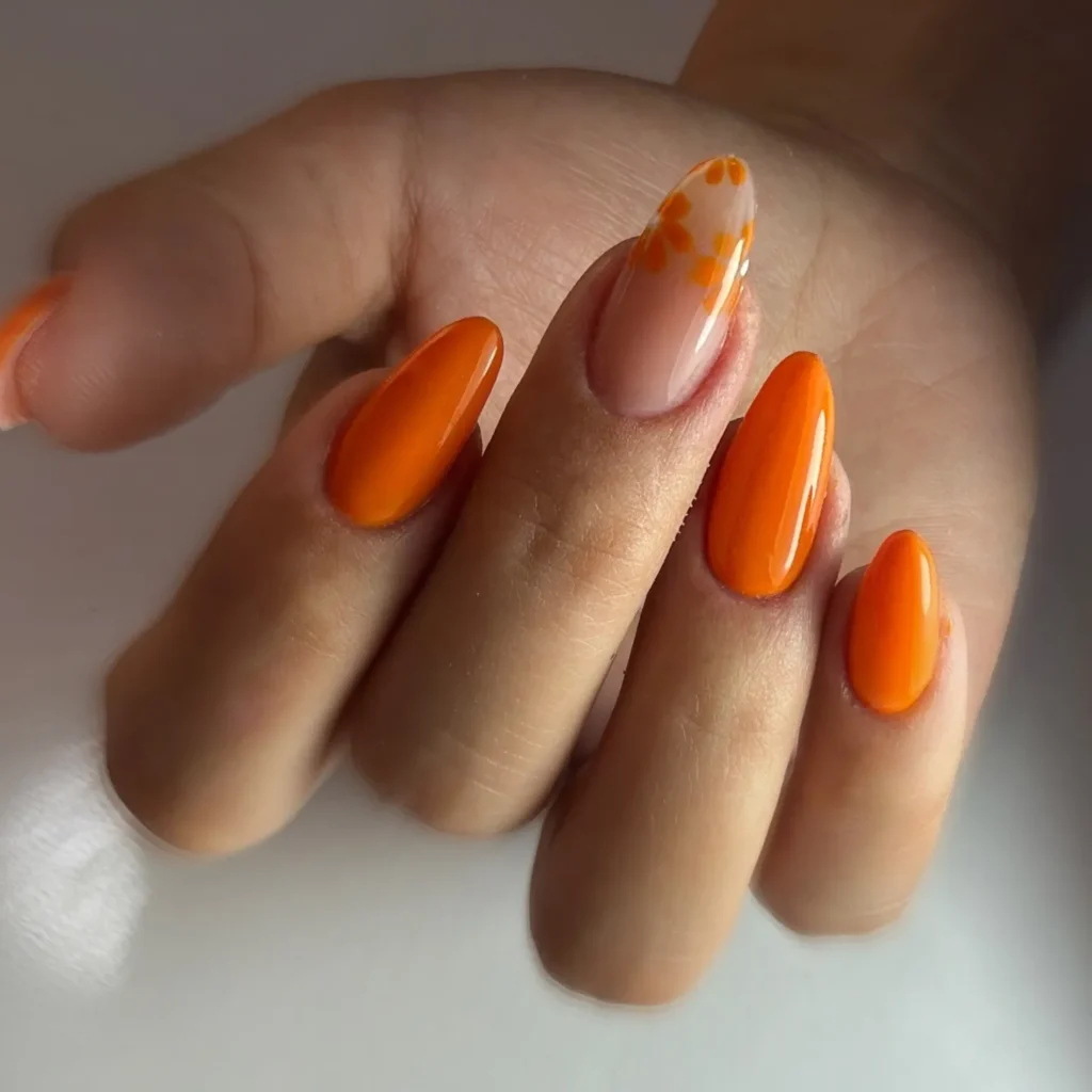 high-gloss orange almond nail look with one hand-painted floral accent nail