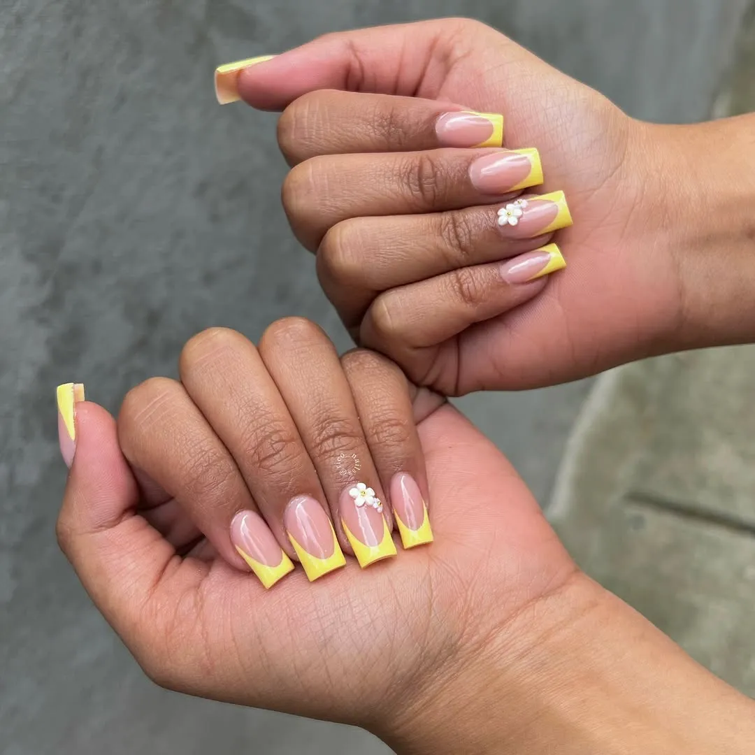 Nude coffin nails with yellow French tips and a white flower charm accent