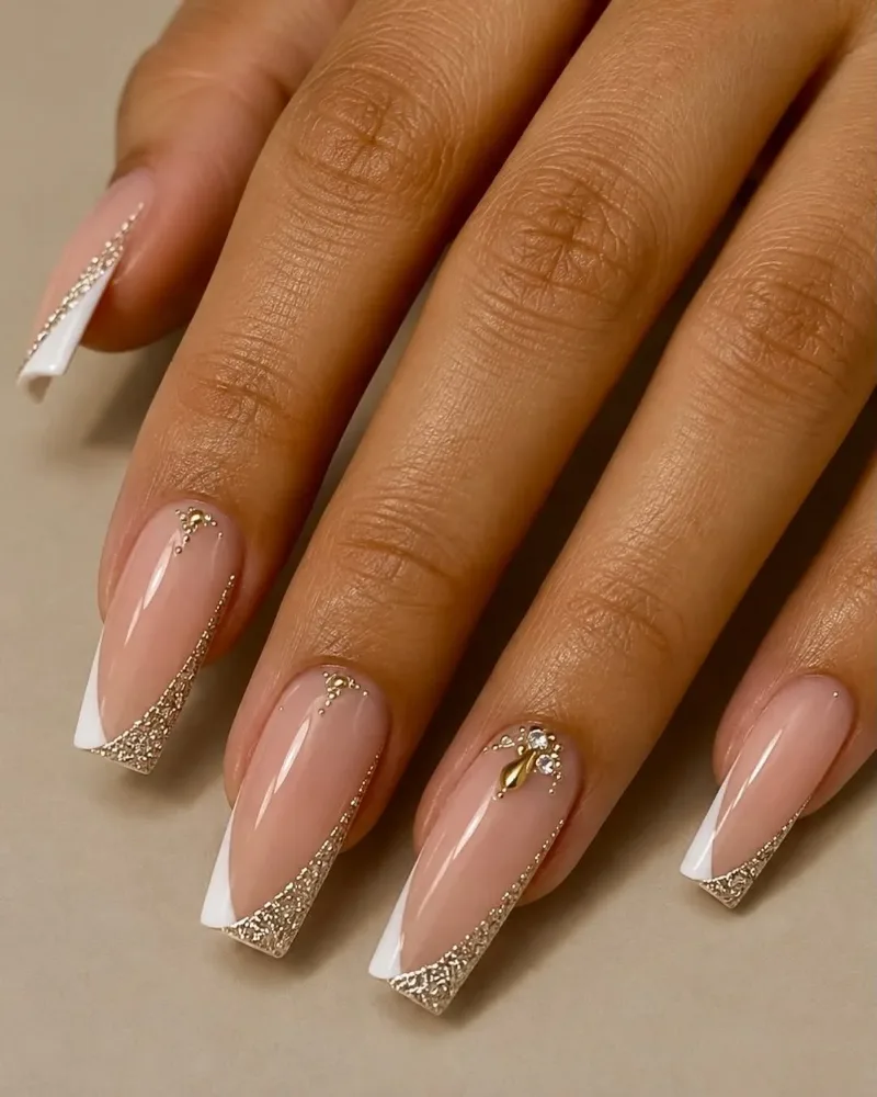 Coffin nails with a nude base, white French tips and gold glitter along the edge