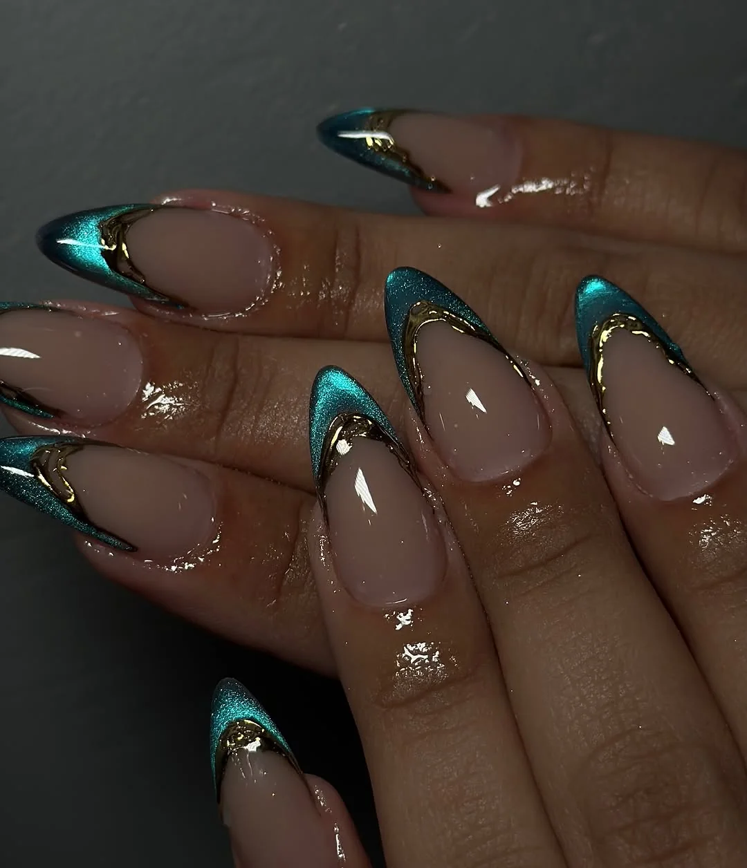 Nude almond nails with teal chrome cat-eye French tips and gold edging