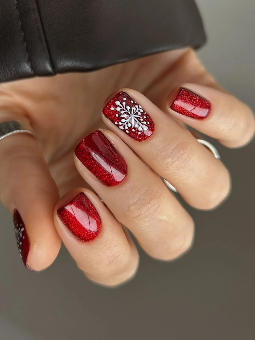 Short red nails with a white snowflake accent nail