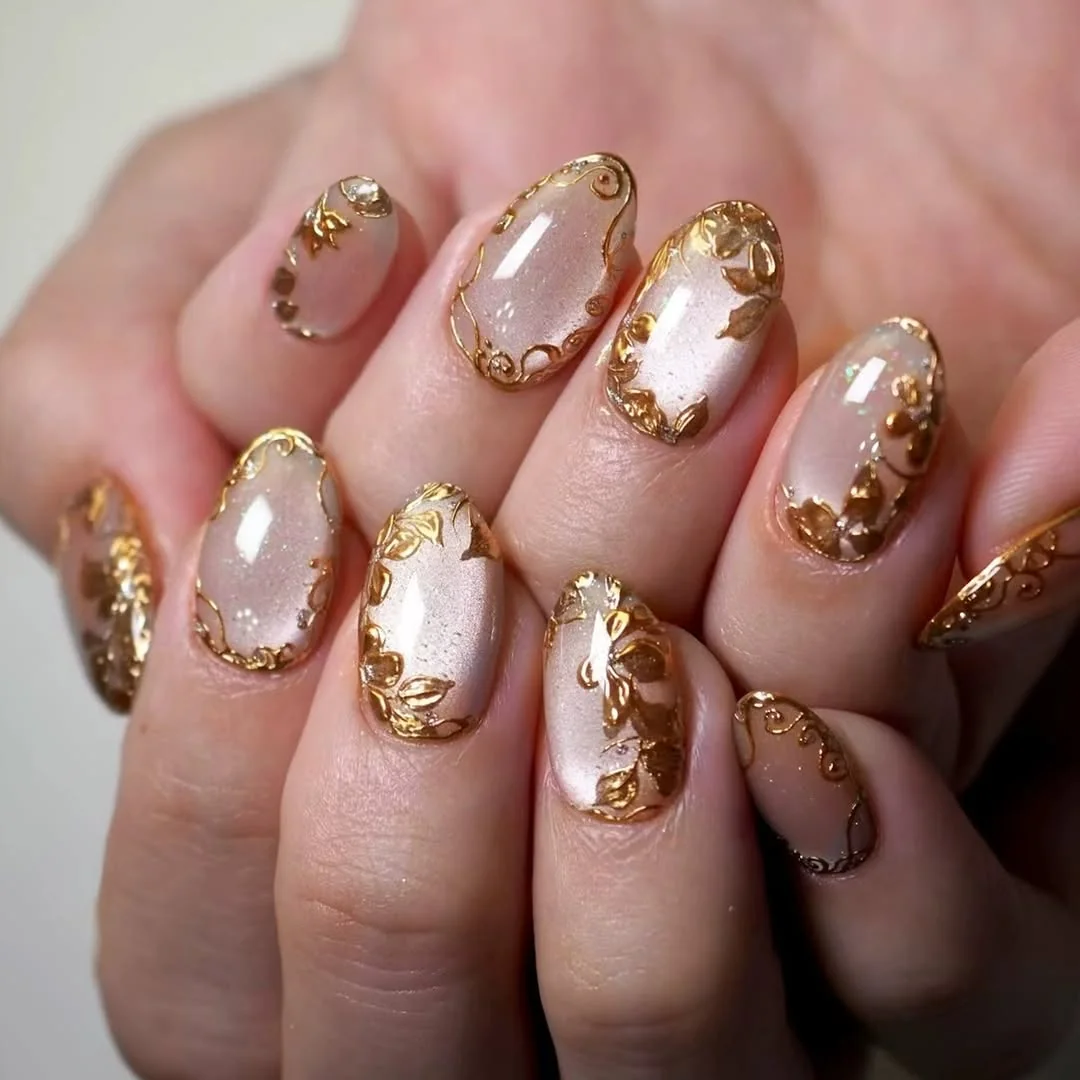 Sheer nude almond nails with gold foil flower designs