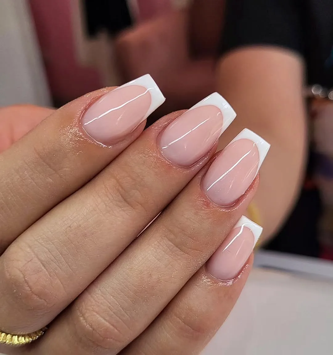 Short square nails with a sheer pink base and white French tips