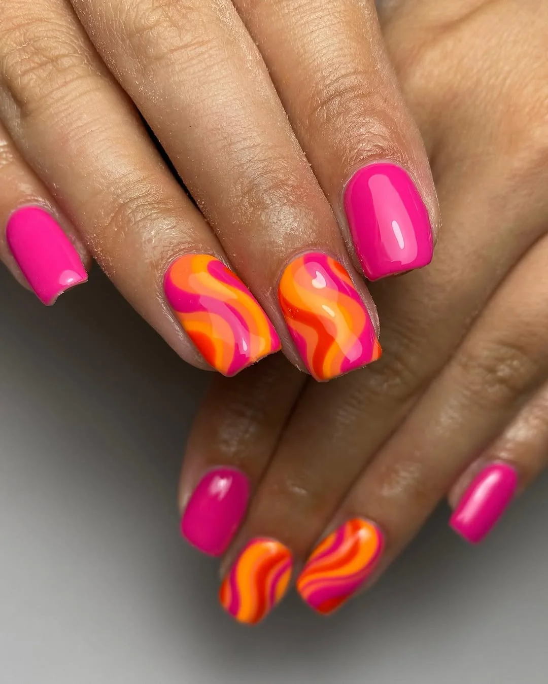 Hot pink nails with orange and pink wavy swirl accents