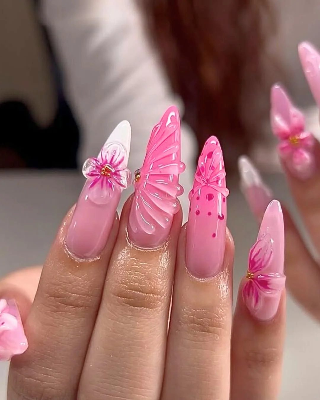 Pink stiletto nails with 3D butterfly wings and flower accents