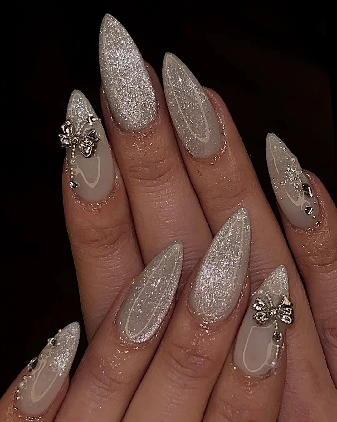 Beige glitter cat-eye almond nails with 3D bow charms