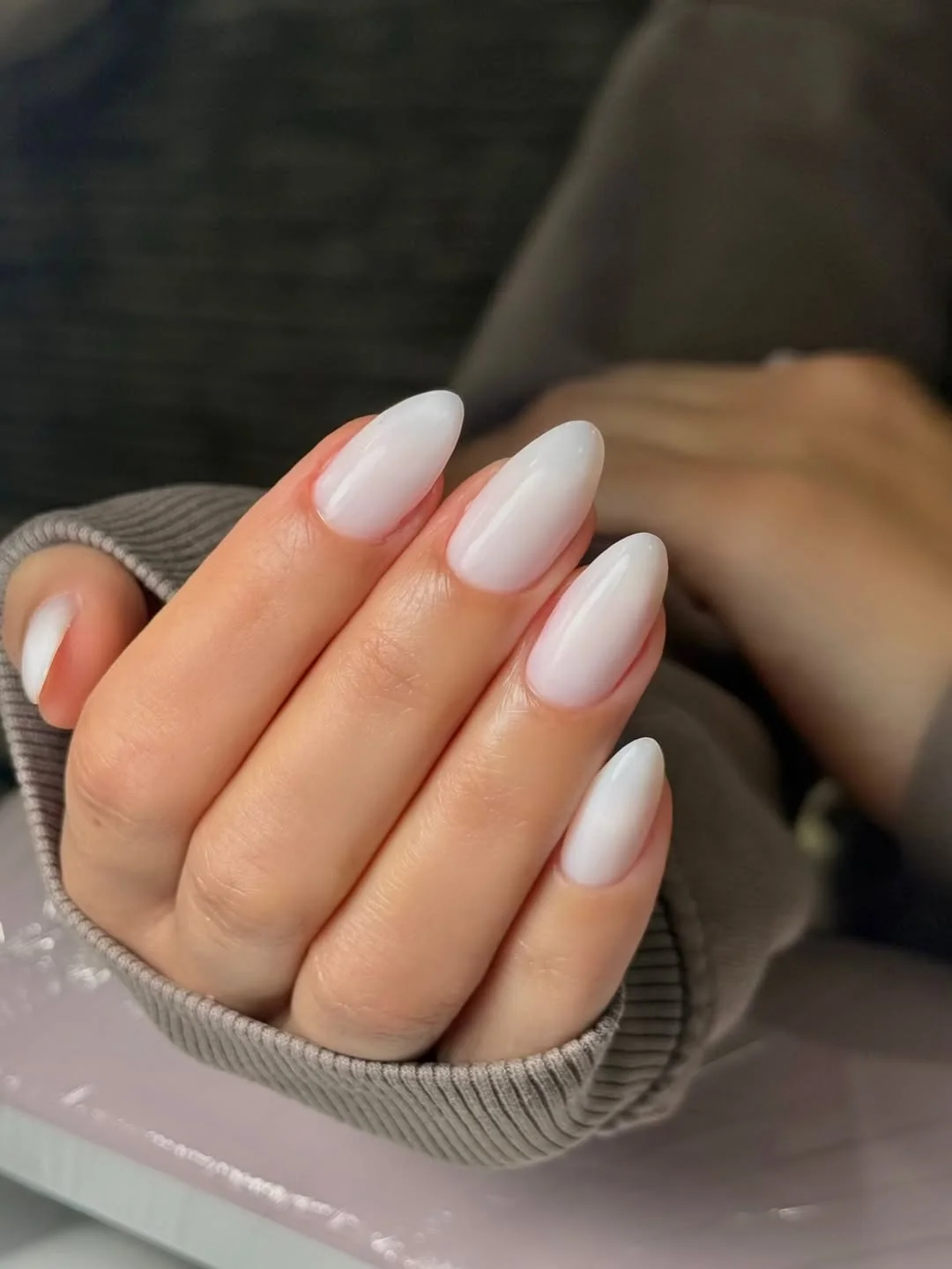 Milky white almond nails on a neutral background