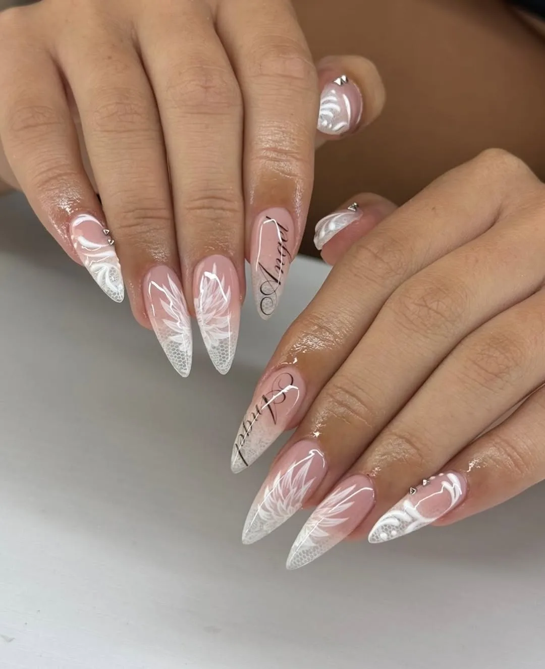 Pink to white ombre long almond nails with white swirl lines and crystals