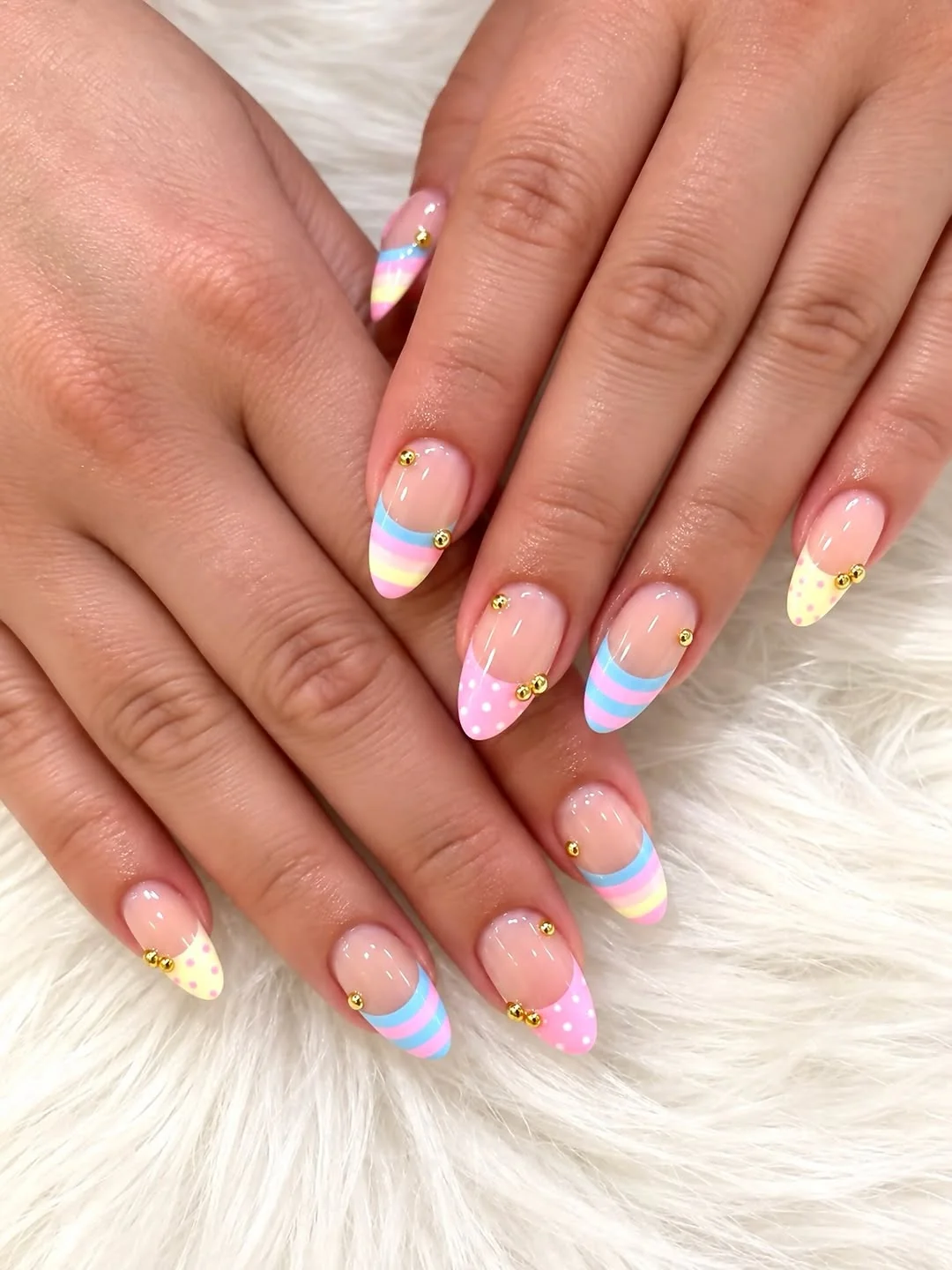 Pastel rainbow French tip almond nails with gold bead accents