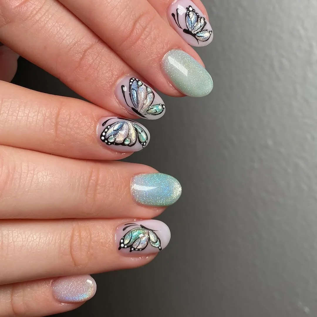 Almond nails with blue and green butterfly wings on pastel shimmer base