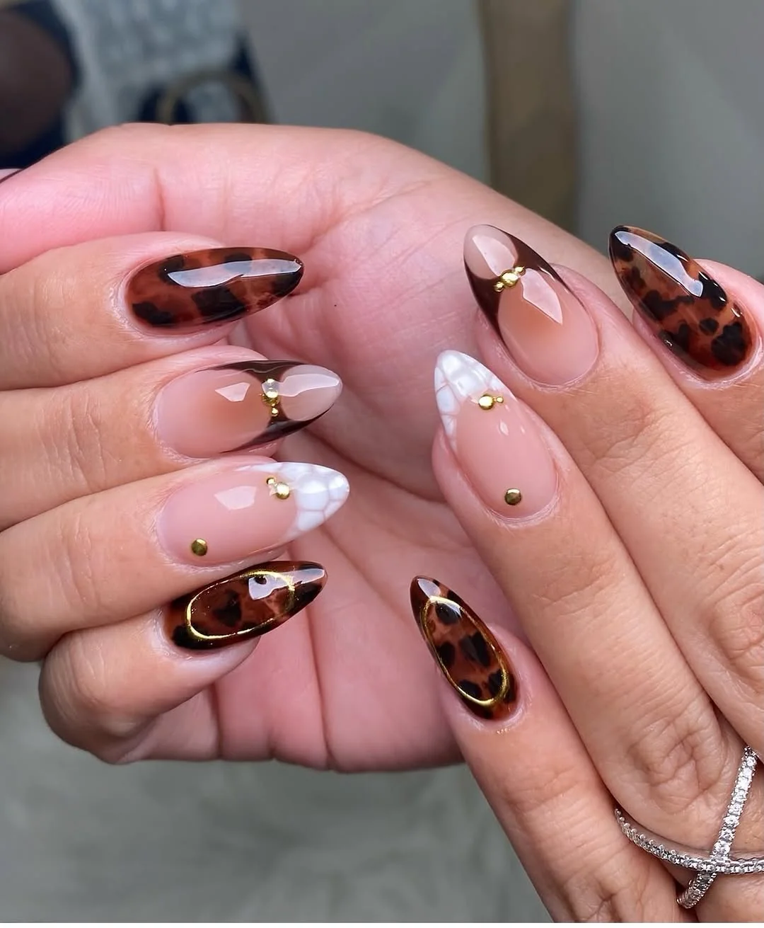 Almond nails with tortoiseshell, gold studs and nude negative space