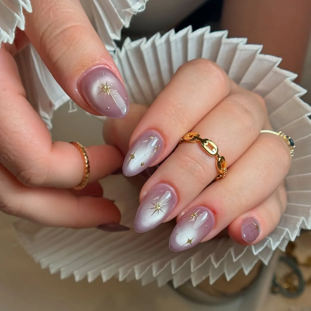 Pearly lavender almond nails with gold starburst accents