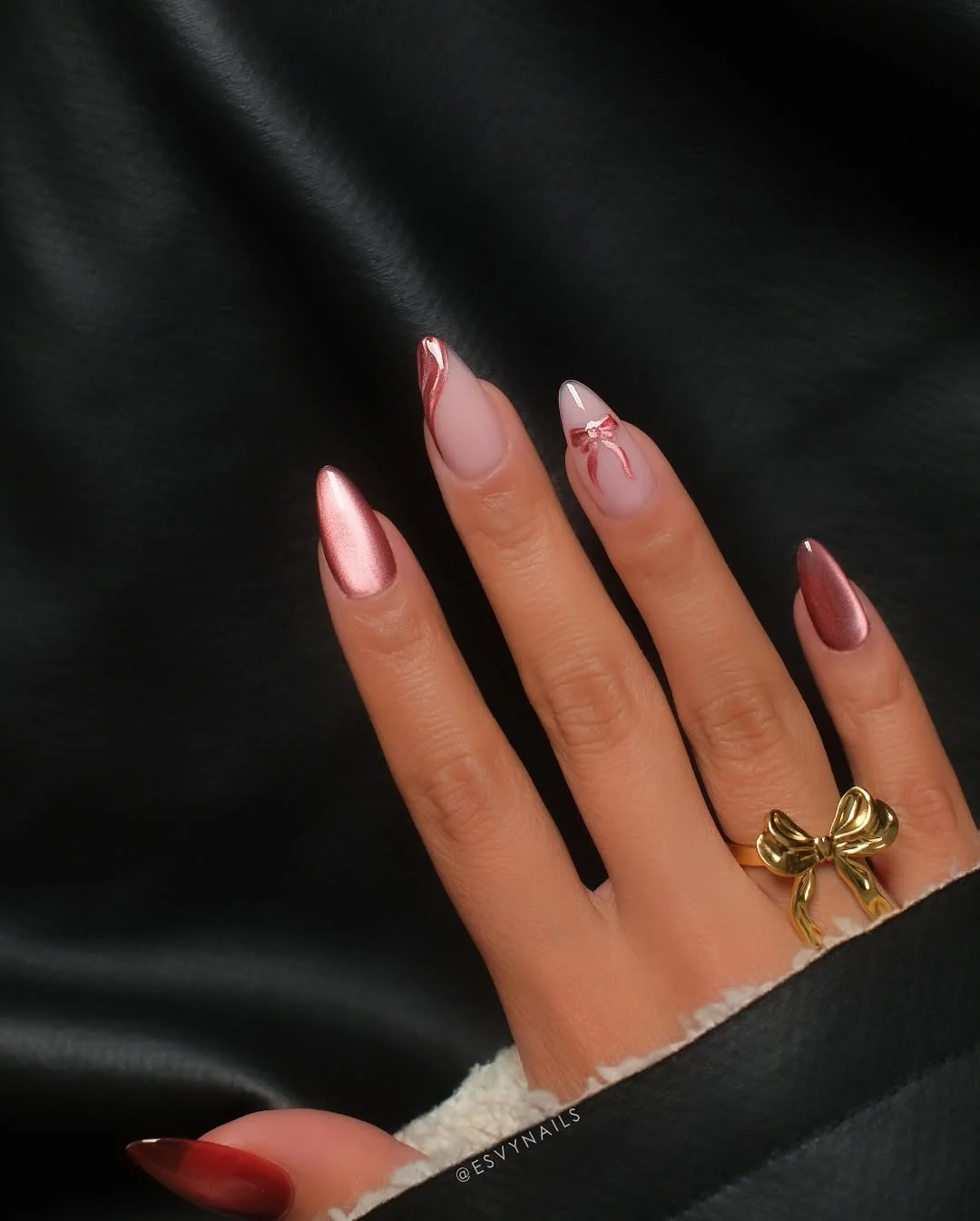 Rose gold chrome almond nails with a gold bow ring