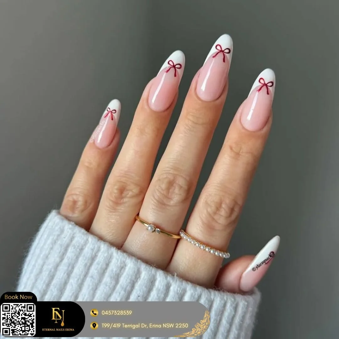Pink almond nails with white tips and red bow accents