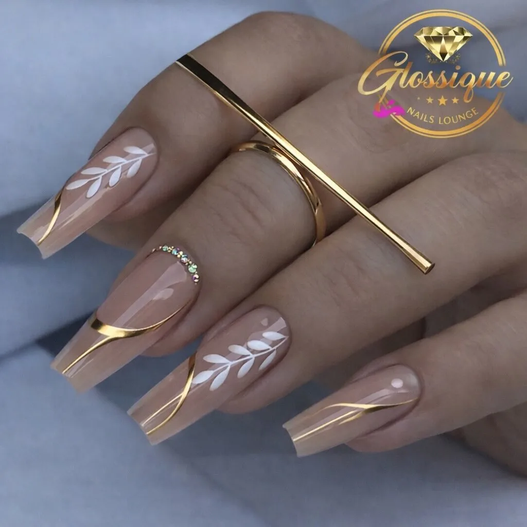 Nude almond nails with gold lines and a white leaf pattern