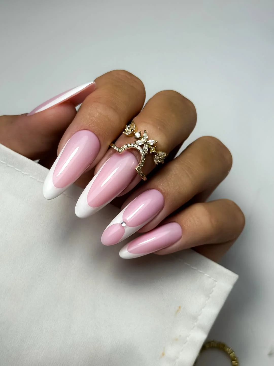 Sheer pink almond bridal nails with white French tips and a pearl