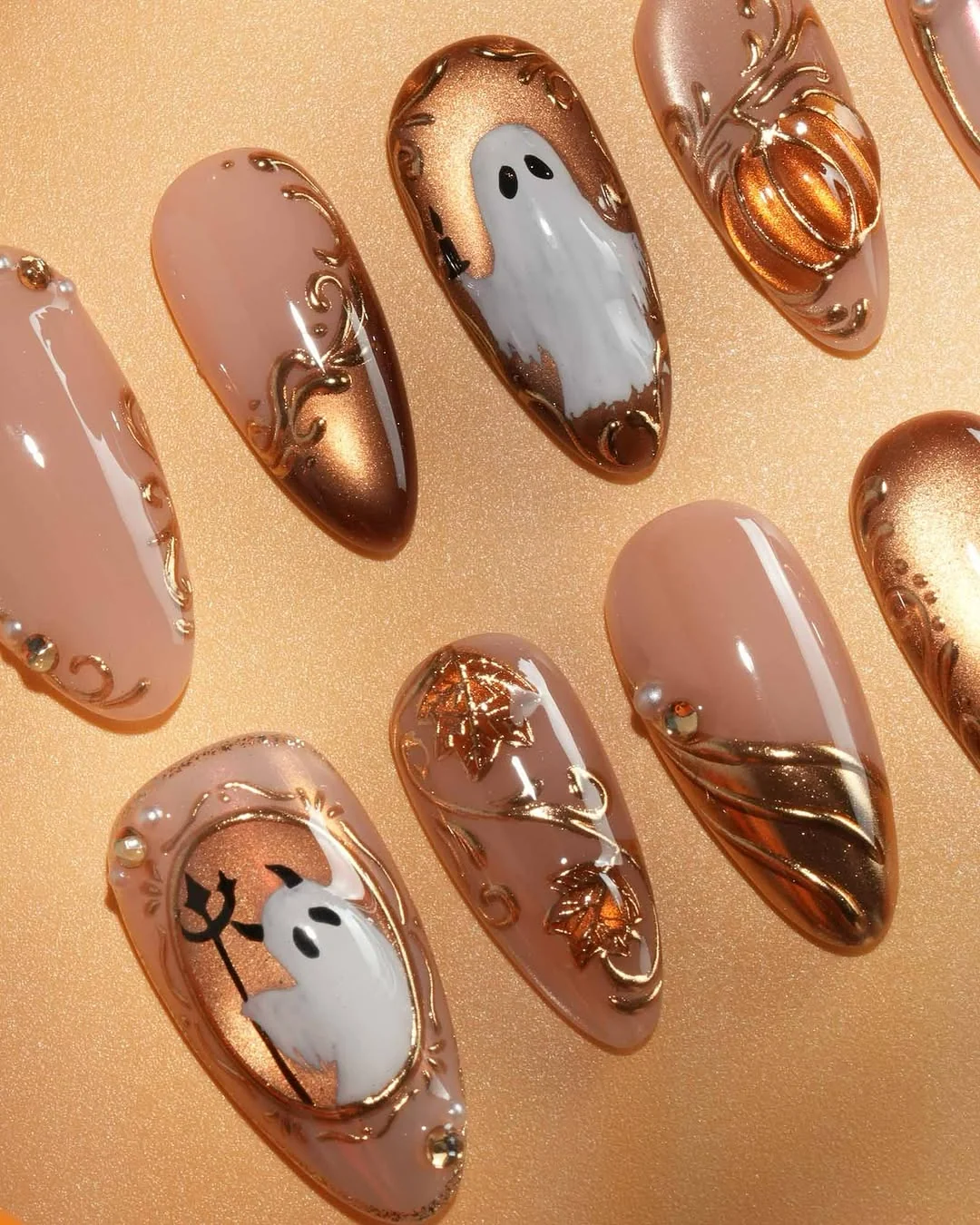 Nude and bronze Halloween almond nails with white ghost and pumpkin charm art