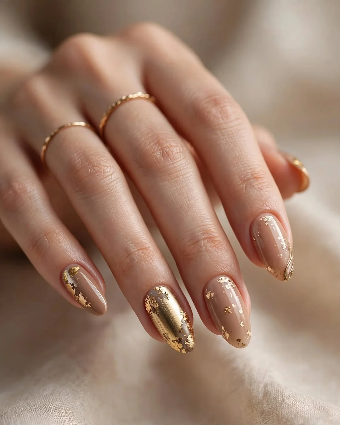 Nude almond nails with gold foil and metallic gold accent nails