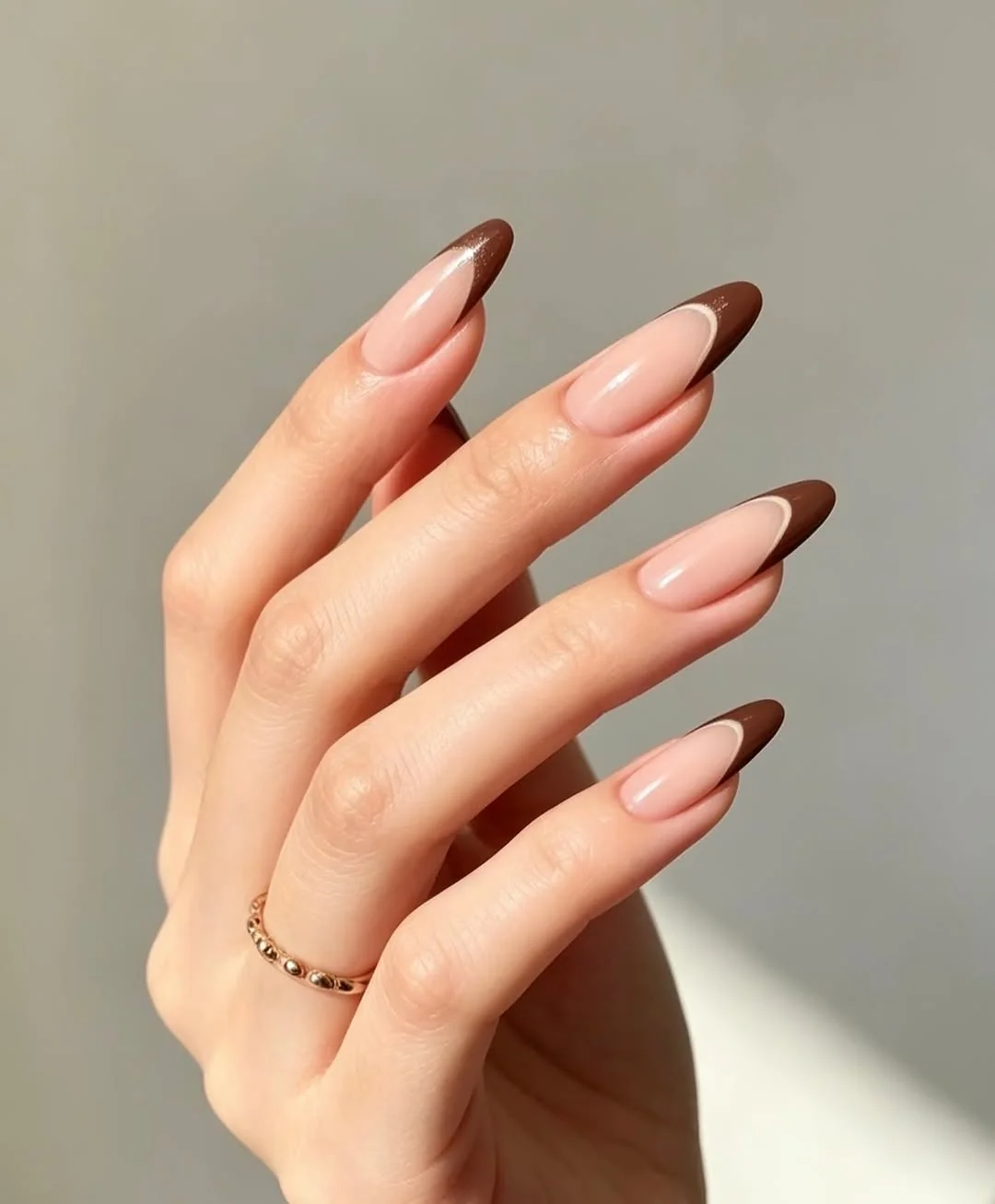 Sheer pink almond nails with chocolate brown French tips
