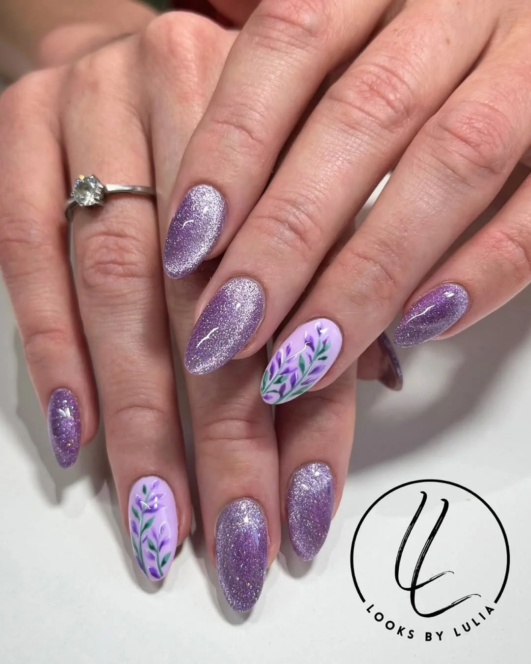 Lavender glitter cat-eye almond nails with a floral accent nail
