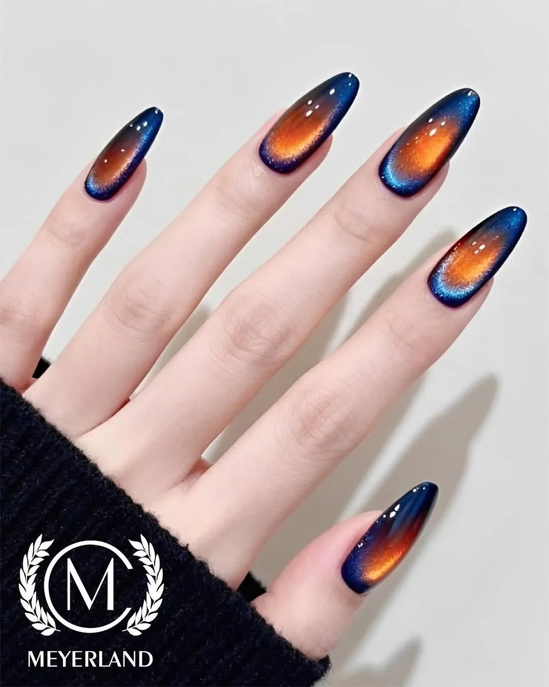 Navy and orange cat-eye almond nails with a glowing center beam