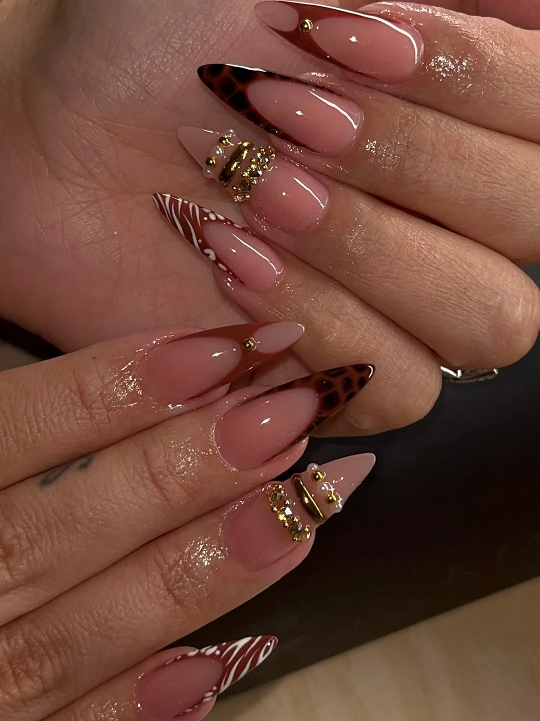Almond nails with brown tortoiseshell tips and candy cane accents on sheer base