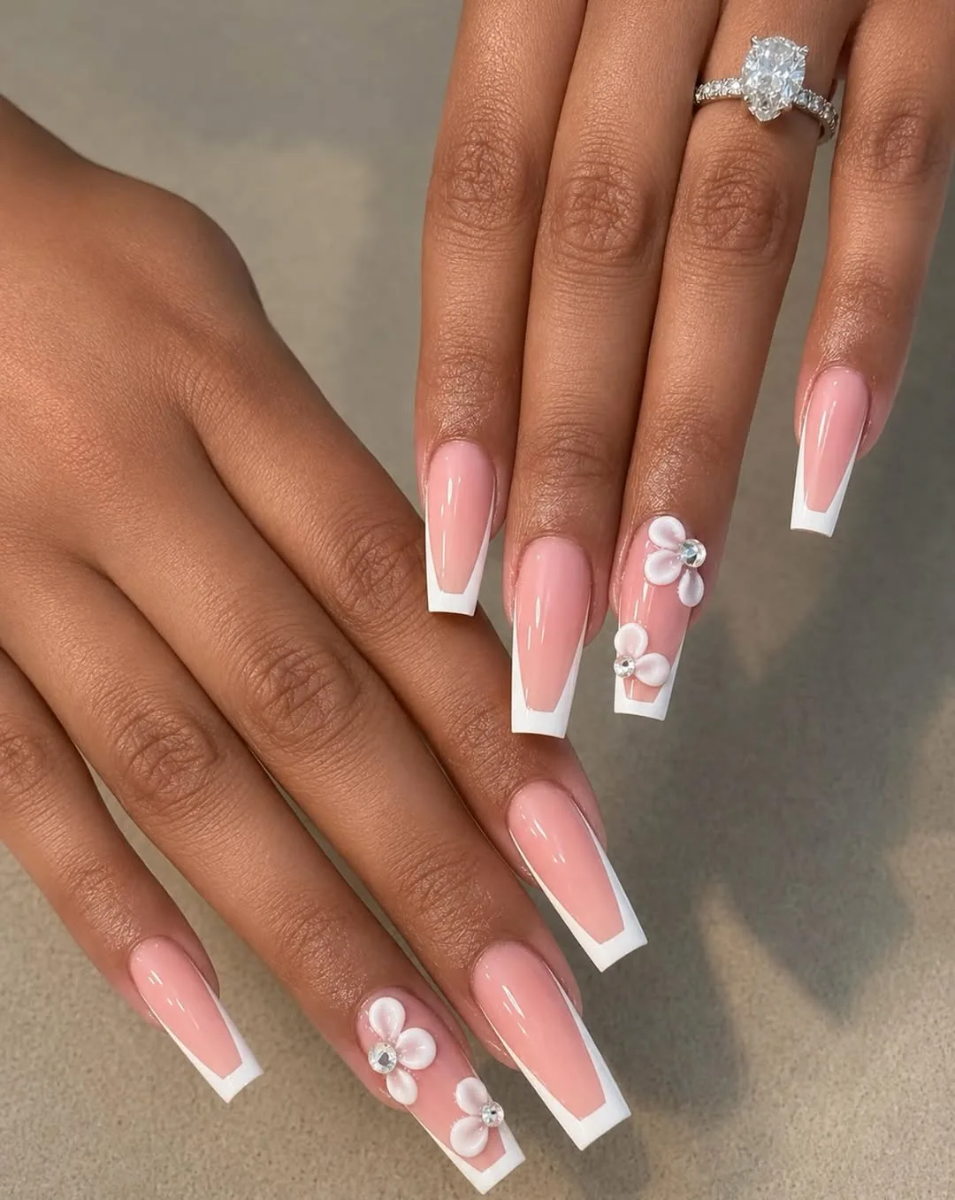 Long coffin nails with a pink nude fade, white tips and small 3D flowers