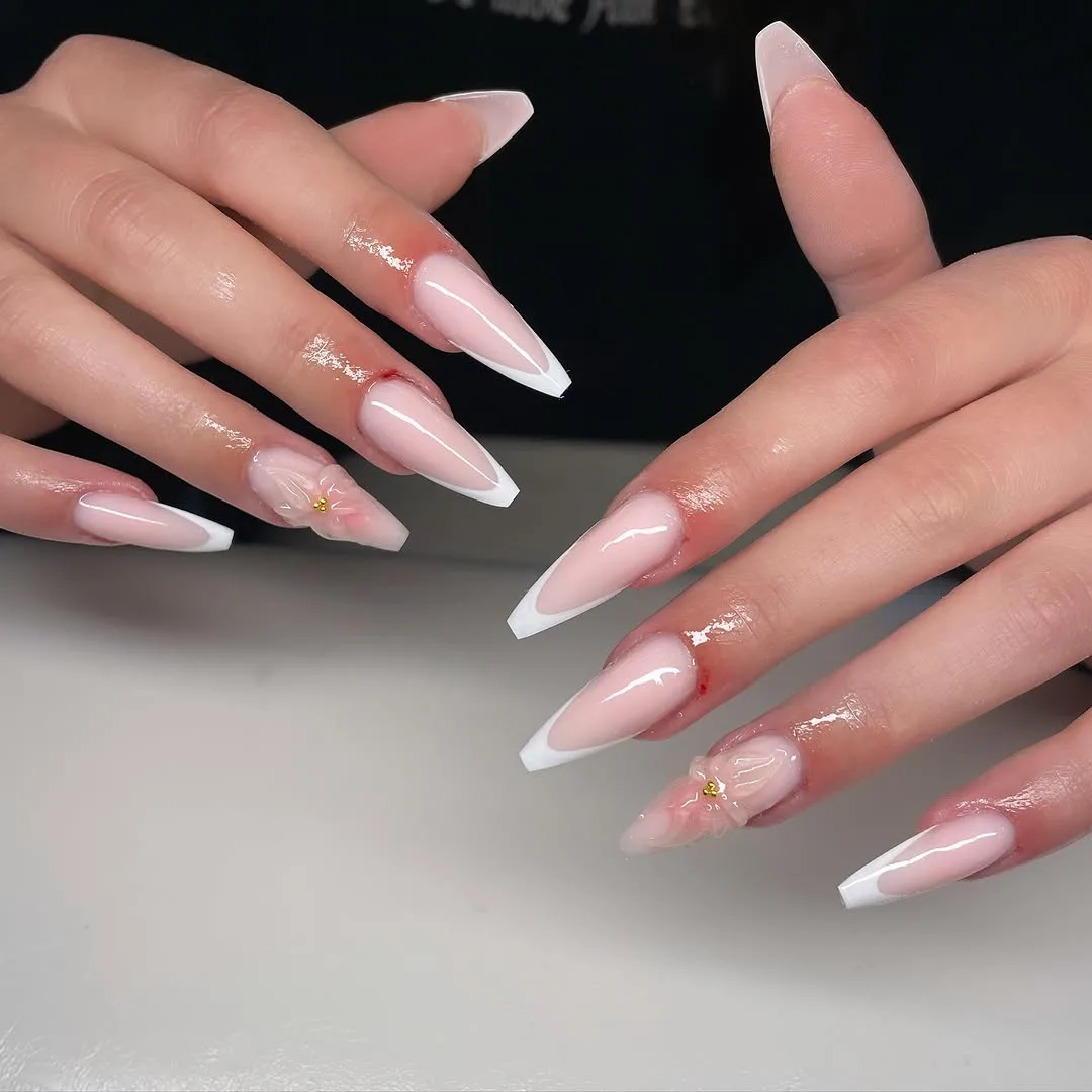 Long almond nails with a soft white ombre fade at the tips and tiny gold bits