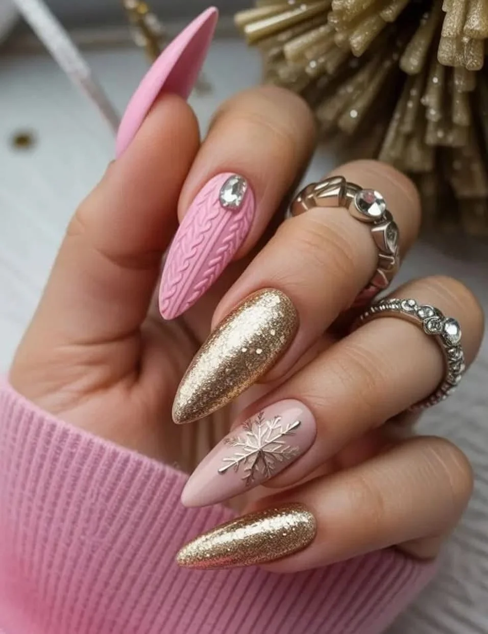 Pink almond sweater nails with knit texture, gold glitter and rhinestone snowflake