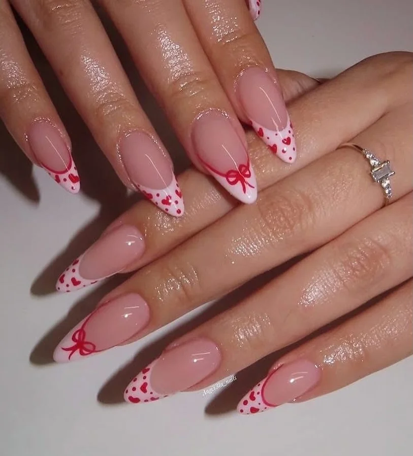Pink French tip almond nails with red bows and heart dots