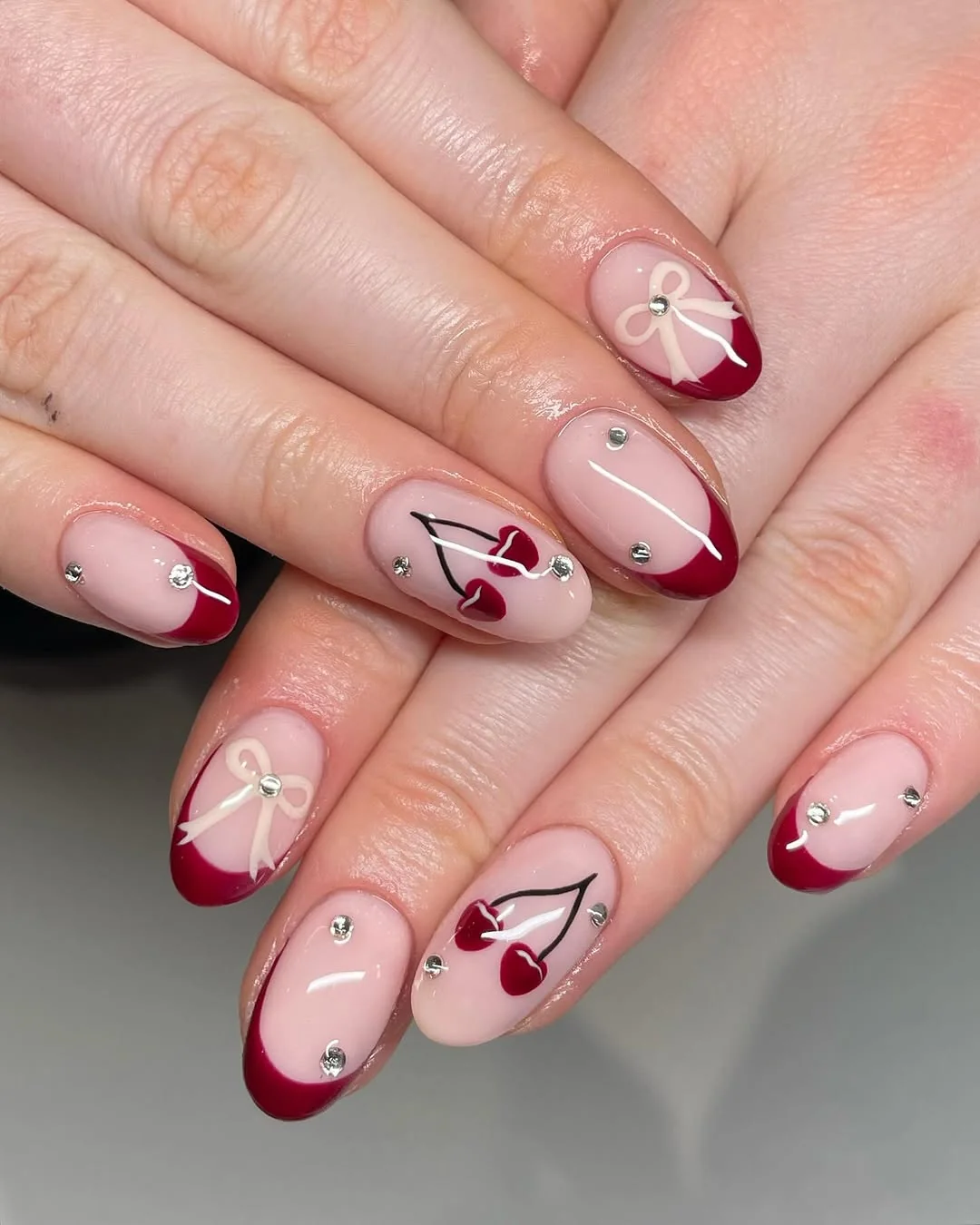 Burgundy French tip nails with cherry art, bows and rhinestones