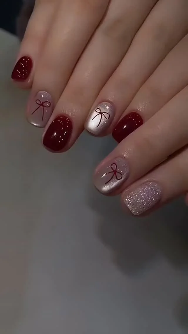 Burgundy glitter short nails with delicate bow outlines
