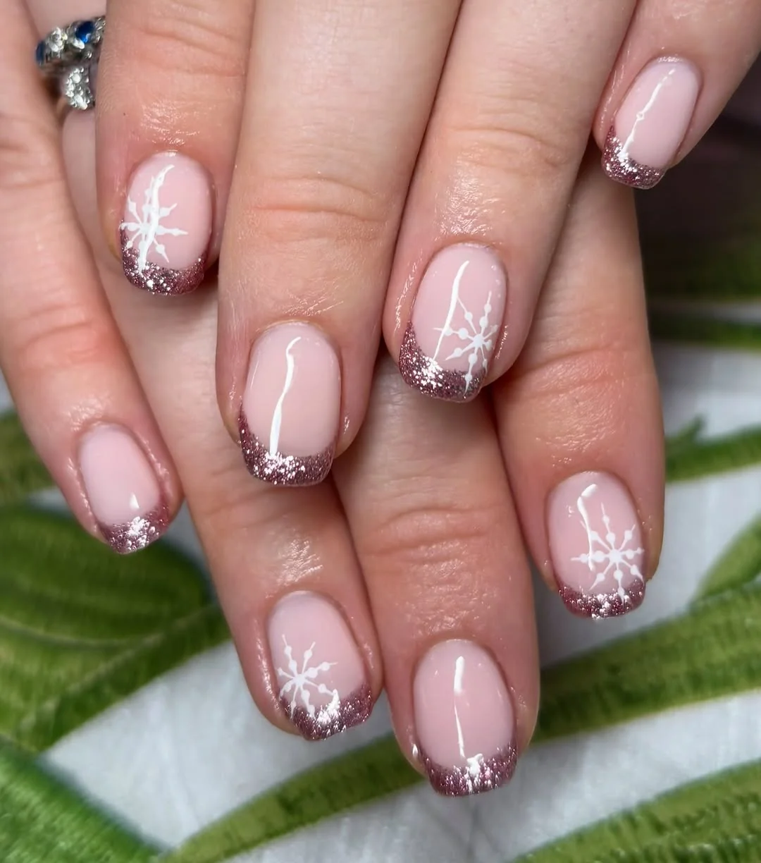 Pink French tip short nails with glitter ombré tips and white snowflakes