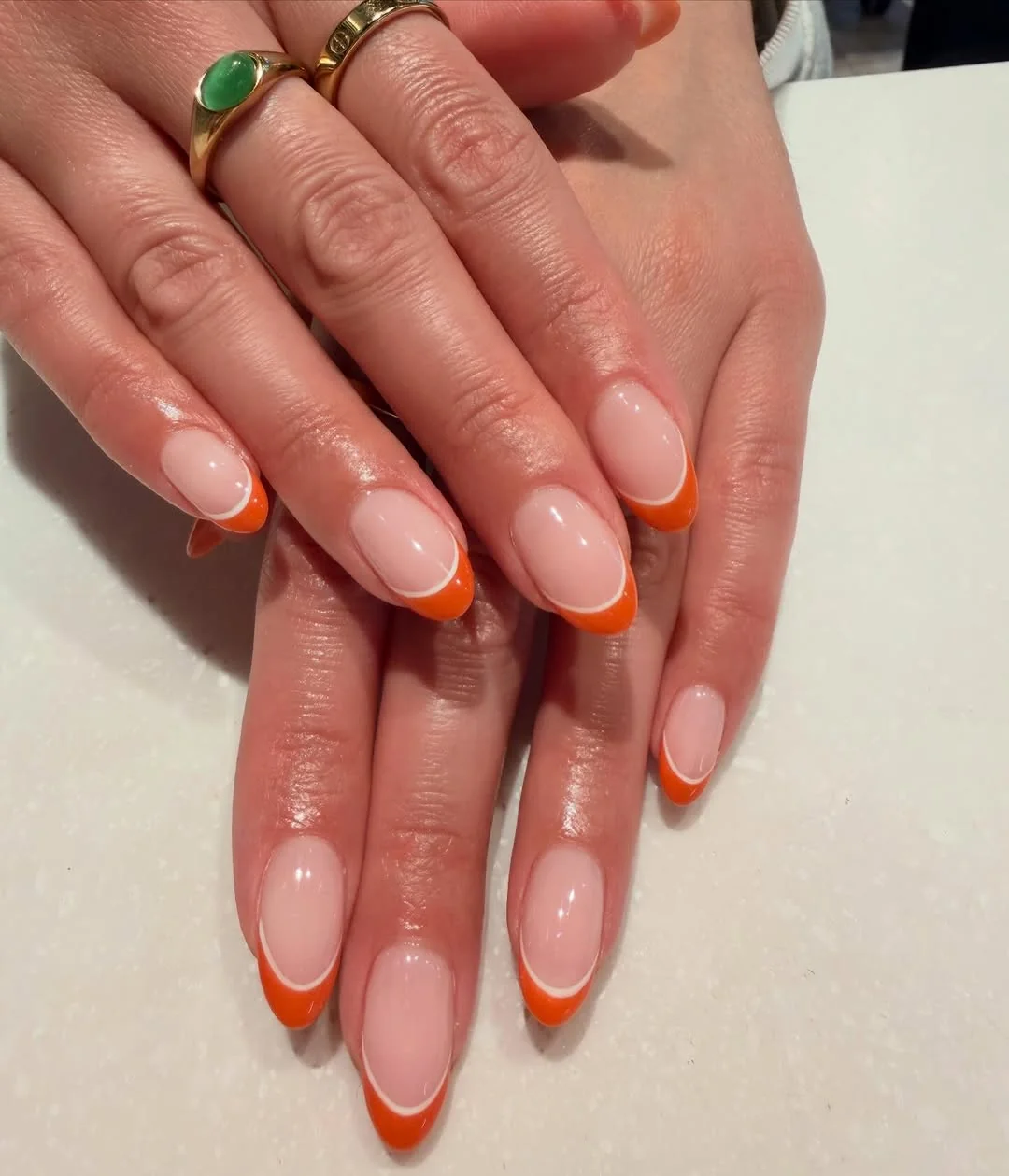 Sheer pink almond nails with burnt orange French tips
