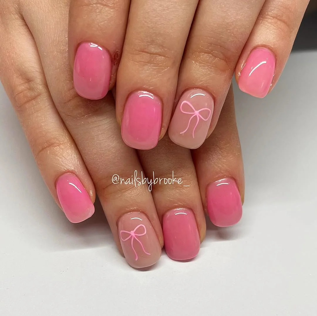 Short pink nails with ribbon bow accent on nude ring finger