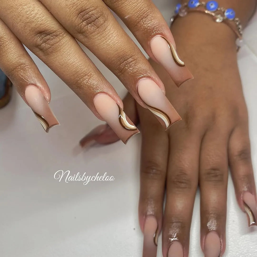 Nude nails with gold swirl lines on medium skin