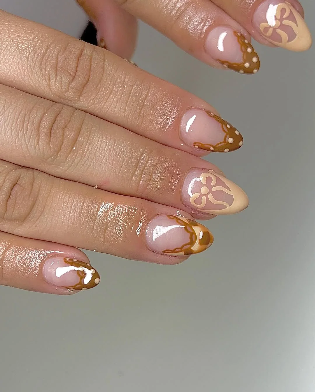 Nude almond nails with gold French tips and small gold foil details